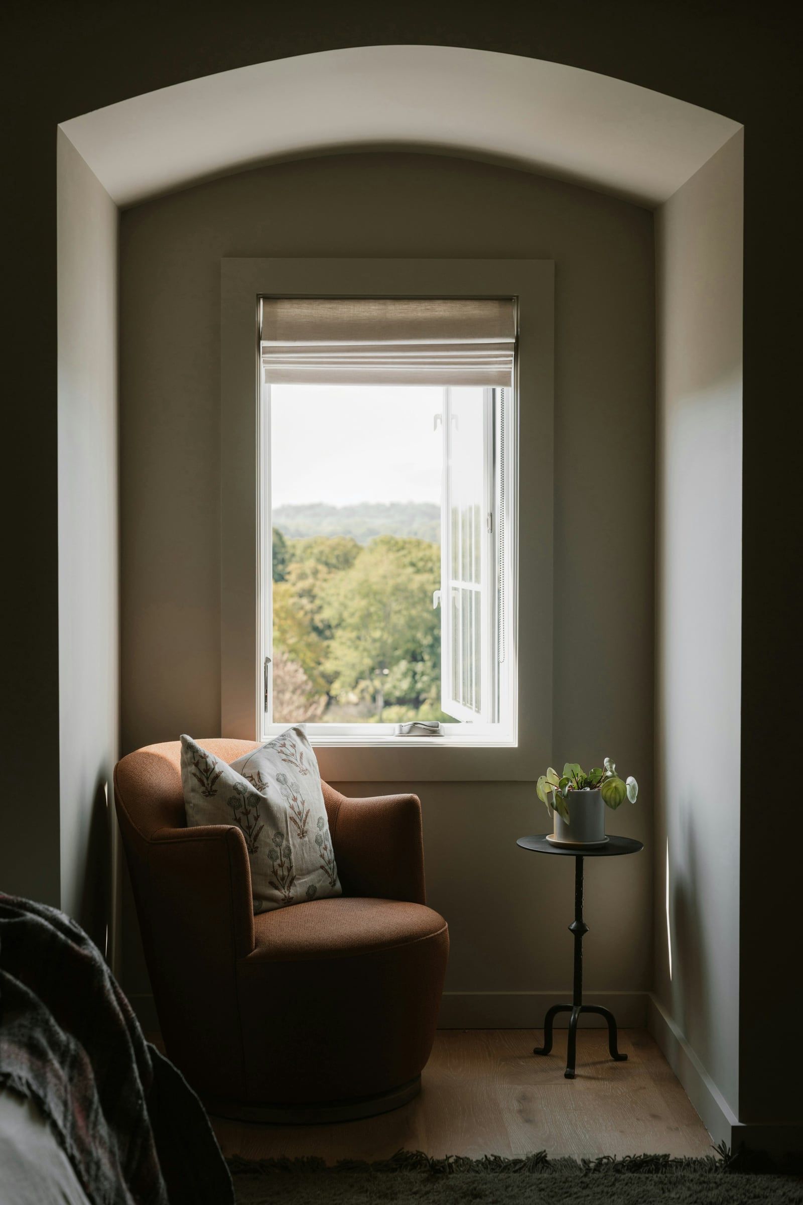 Photo d’illustration : un fauteuil et un coussin près d’une fenêtre ouverte sur la verdure.